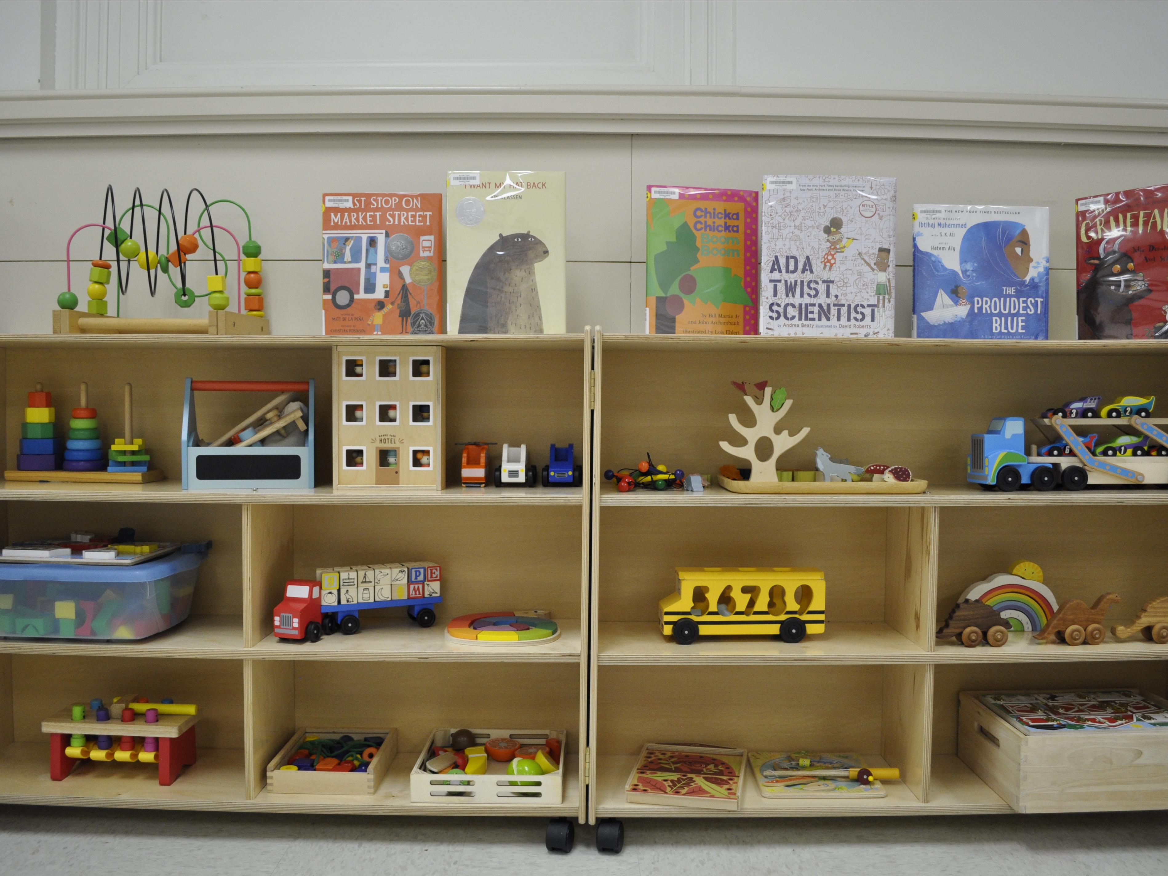 A book shelf with children's picture books and wooden toys.